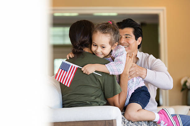 A family embracing at home, a child holding a small U.S. flag