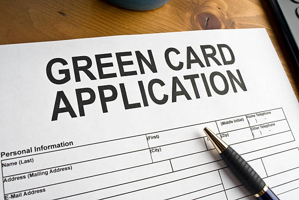 A green card application form with a pen