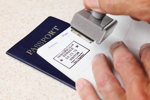An officer stamping a passport with a visitor stamp