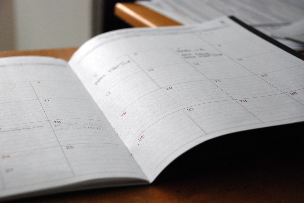 Open monthly paper planner lying on a wooden desk