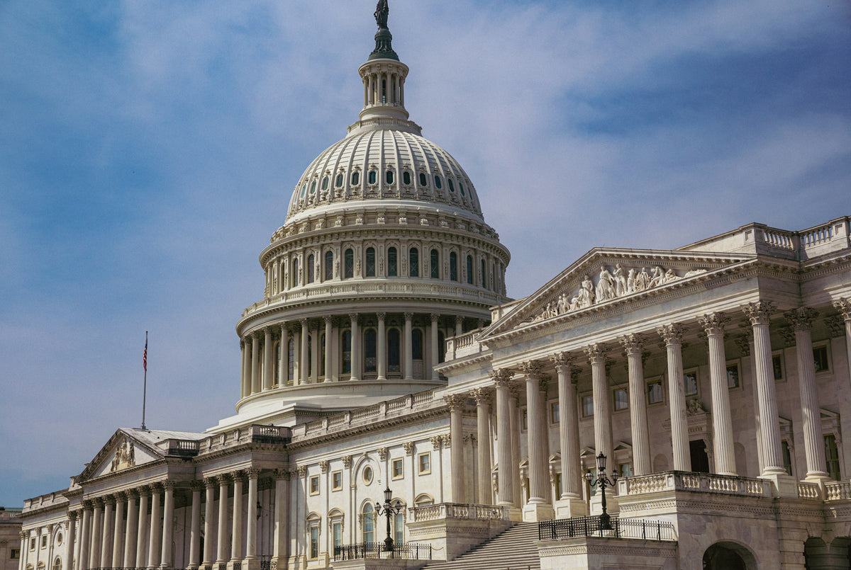 U.S. Capitol dome and west front under a blue sky with clouds