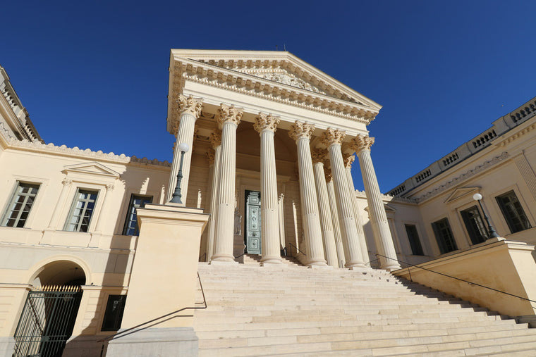 Neoclassical courthouse facade with tall columns and wide stone steps under a blue sky