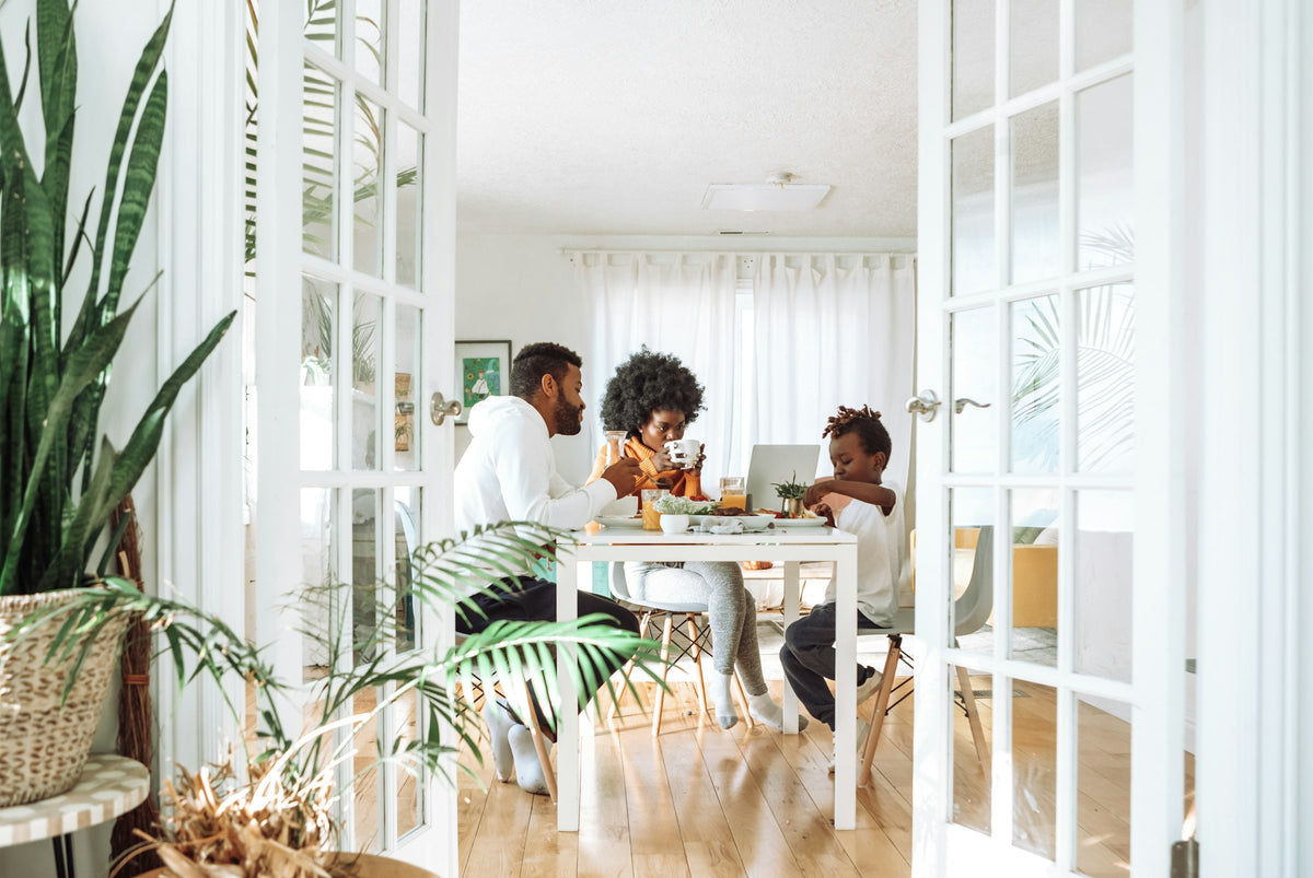 Family with two young children sharing a meal at a dining table in a bright home