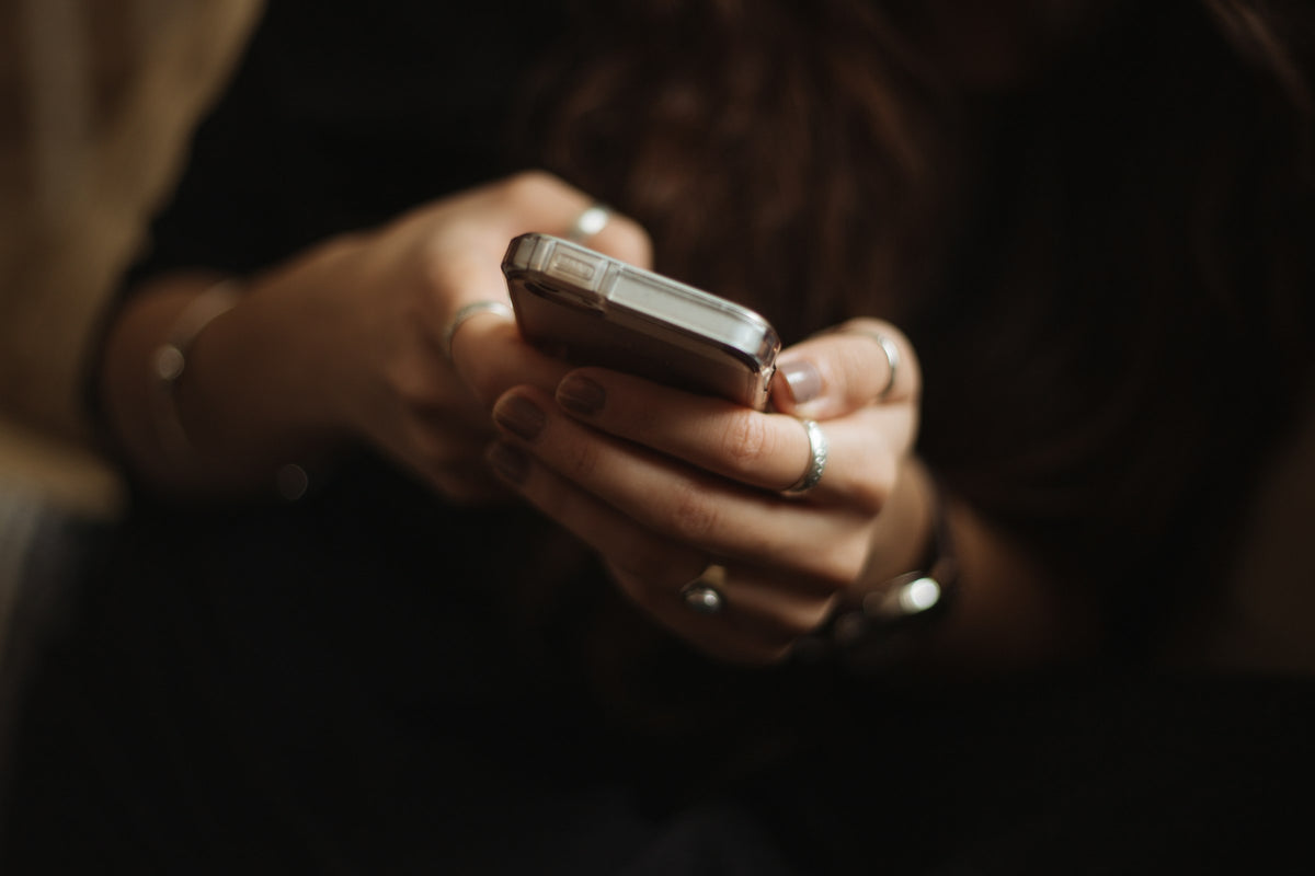 Close-up of a woman's hands holding and scrolling a smartphone in low light