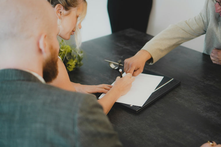 Couple signing a document across a desk from an advisor in a suit