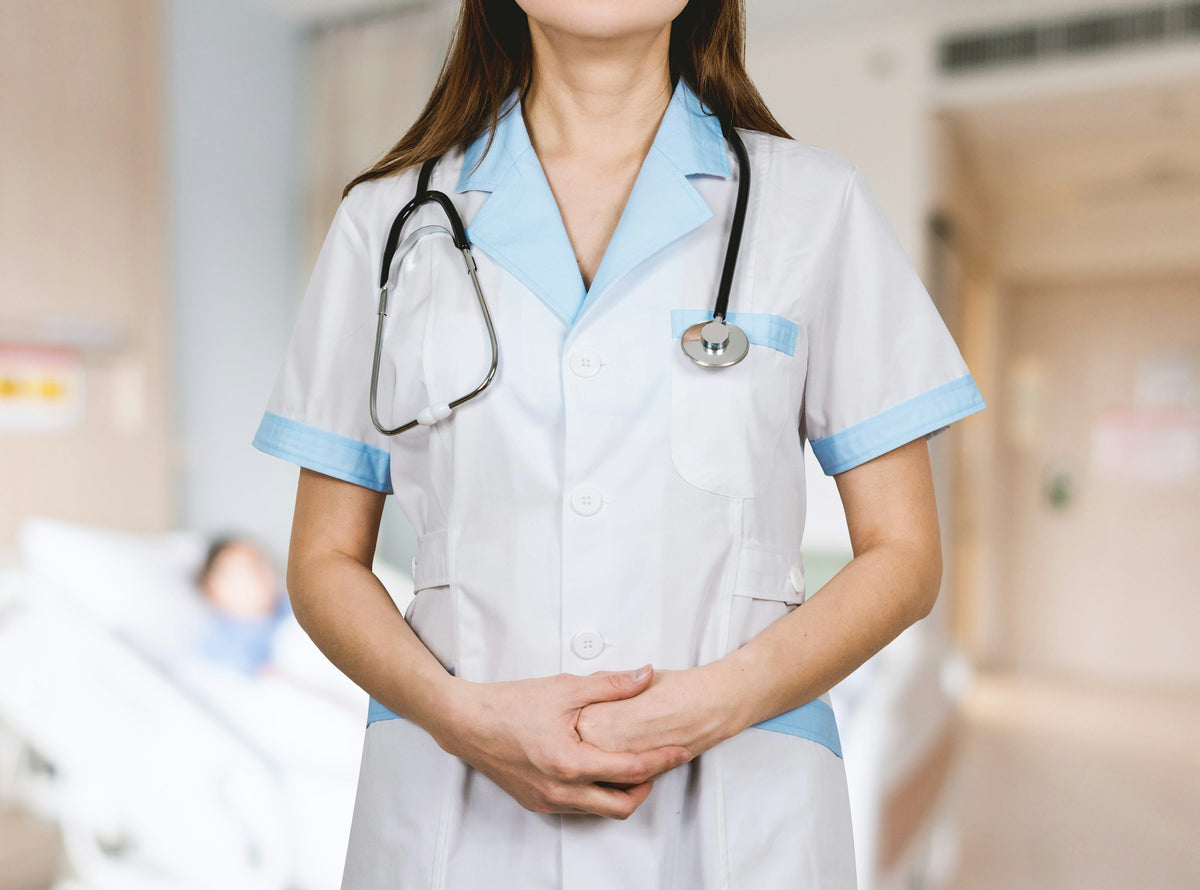 Healthcare worker in a white uniform with a stethoscope standing in a hospital room