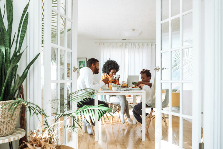 Family with two young children sharing a meal at a dining table in a bright home