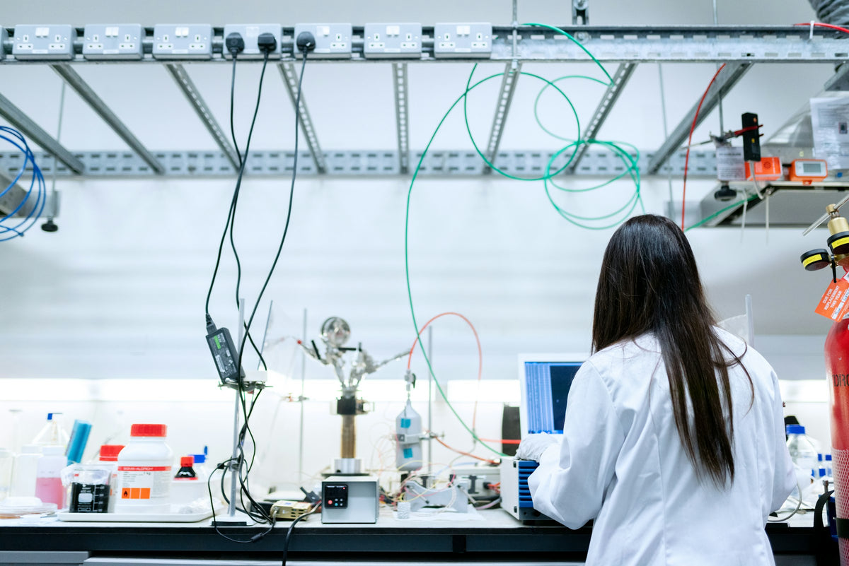 Female scientist in a white lab coat working at a laptop in a laboratory