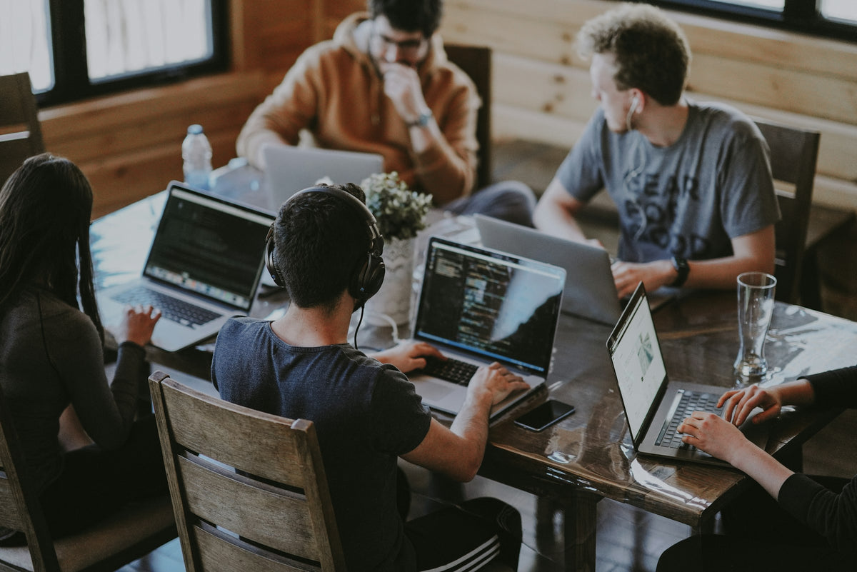 Team of young professionals working on laptops around a shared table
